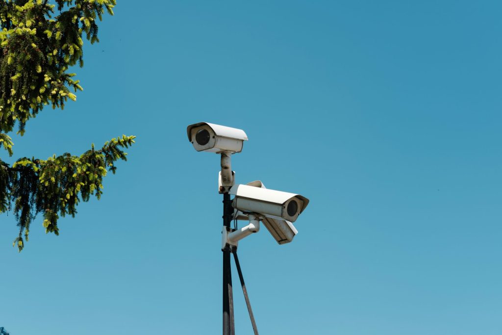 Multiple security cameras mounted on a pole against the sky.